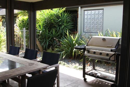 a grill on a patio with a table and chairs at Quantum Lodge Motor Inn in Hamilton