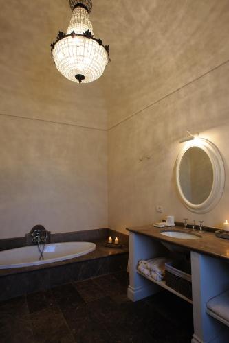 a bathroom with a tub and a sink and a chandelier at Castello Camemi in Vizzini