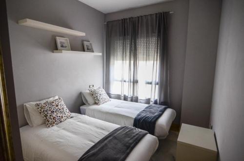 - une petite chambre avec 2 lits et une fenêtre dans l'établissement Marqués de San Lorenzo -2 dormitorios & FREE parking, à Séville