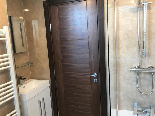 a bathroom with a shower and a wooden door at The savoy apartment in Douglas