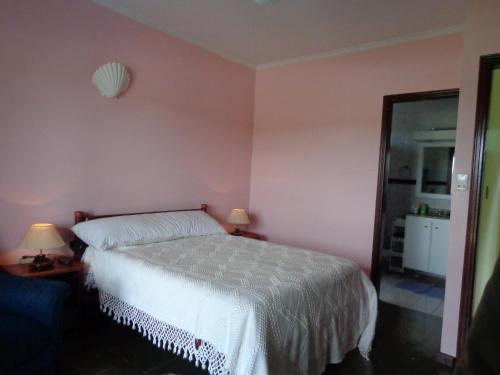 a bedroom with a white bed and a pink wall at Casa Tacumsol in Fama