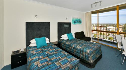 una habitación de hotel con una cama y un balcón en Atlantic Tower Motor Inn, en Adelaida