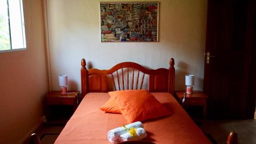 a bedroom with a bed with an orange bedspread and two lamps at Chez Momo et Dany in Deshaies