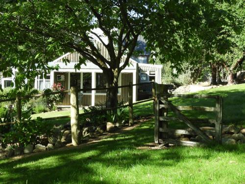 a fence and a tree in front of a house at O Naturel Vineyard Stay in Cromwell
