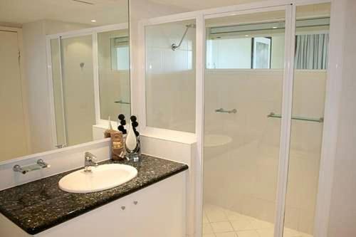a white bathroom with a sink and a shower at Lagoon Beachfront Lodge 005 on Hamilton Island by HamoRent in Hamilton Island