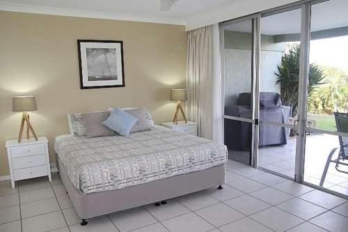 1 dormitorio con 1 cama y puerta corredera de cristal en Lagoon Beachfront Lodge 005 on Hamilton Island by HamoRent, en Hamilton Island