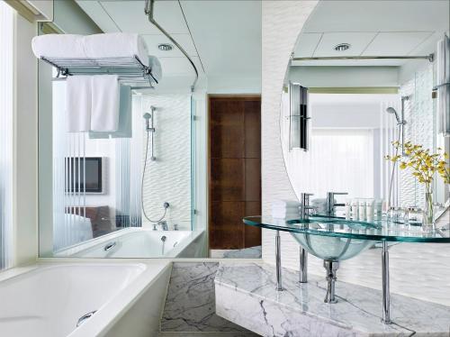 a bathroom with a tub and a glass table at Cordis, Hong Kong in Hong Kong