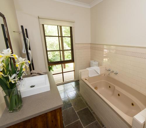 a bathroom with a tub and a sink and a mirror at Hollyhock in Macedon