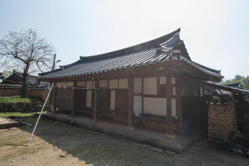 a small house with a black roof in a yard at Jinrae Lee's Traditional House in Boseong