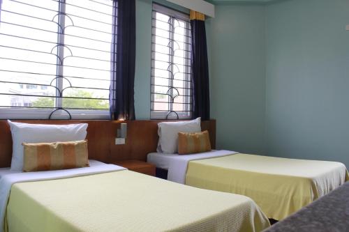 Leesons Residences في مانيلا: سريرين في غرفة بها نافذتين