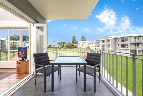 a patio area with chairs, tables, and a balcony at Mantra Lorne in Lorne