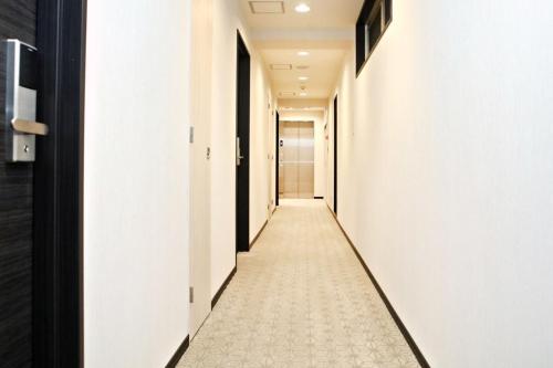 a hallway with white walls and a tile floor at Toho Hotel in Osaka