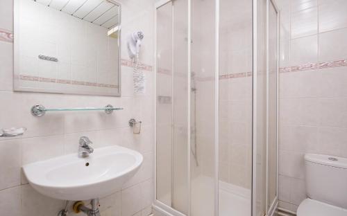 uma casa de banho branca com um lavatório e um chuveiro em TransHotel em Ecaterimburgo