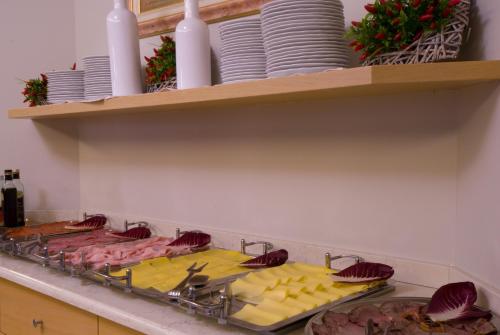 a kitchen counter with meat and cheese and plates on shelves at Hotel Oasi Wellness & Spa in Riva del Garda
