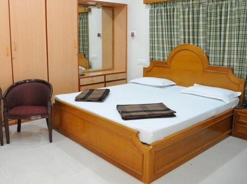 a bedroom with a large bed and a chair at Lloyds Guest House, North Boag Road, T. Nagar in Chennai