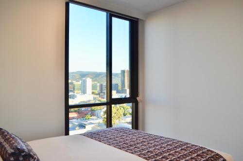 a bedroom with a bed and a large window at Whitmore SQ in Adelaide