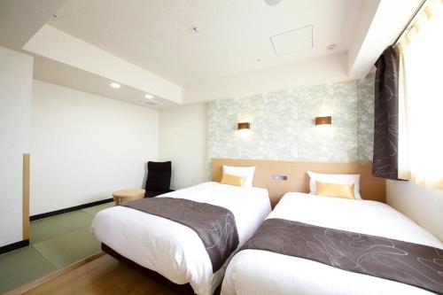 a bedroom with two beds and a window at Hotel Lifetree Hitachinoushiku in Ushiku