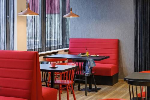 a restaurant with two tables and red chairs at ibis Styles Halle in Halle an der Saale
