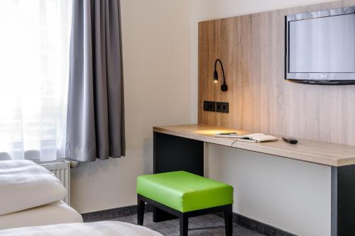 a room with a desk and a green stool at ibis Styles Halle in Halle an der Saale