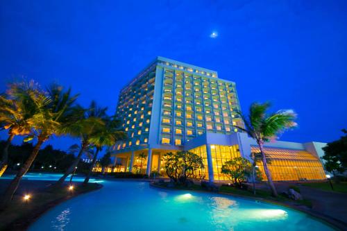 a hotel with a swimming pool in front of a building at Laguna Garden Hotel in Ginowan
