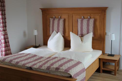 a bed with a wooden head board and white pillows at Posthotel Arnold in Gunzenhausen