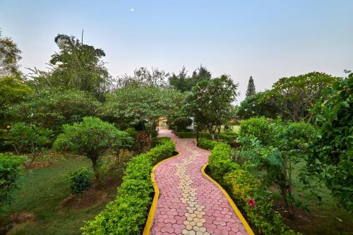 a stone path in a garden with trees and bushes at Aacorn Hideaway Resort & Spa in Rāmnagar
