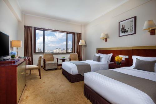 昆明市にある昆明 ジンジャン ホテルのベッド2台とテレビが備わるホテルルームです。