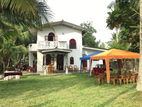 ein weißes Haus mit Tischen und Stühlen im Hof in der Unterkunft Raj Villa Kumarakanda Hikkaduwa in Hikkaduwa