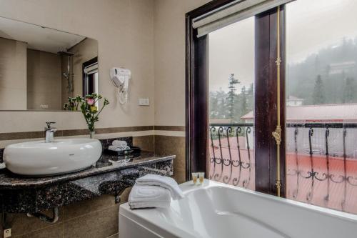 a bathroom with a tub and a sink and a window at Delta Sapa Hotel - Old Quarter Center in Sa Pa