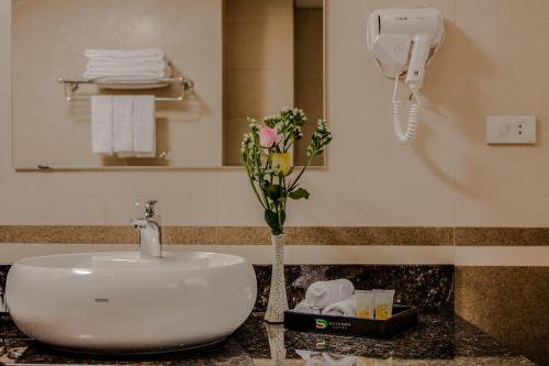 a bathroom sink with a vase of flowers on a counter at Delta Sapa Hotel - Old Quarter Center in Sa Pa