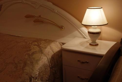 a lamp on a dresser next to a bed at Nelly Apart in Kyiv