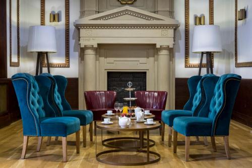 a room with chairs and a table and a fireplace at Boutique Hotel H10 Villa de la Reina in Madrid