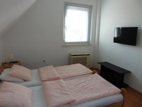 sypialnia z łóżkiem z różową pościelą i oknem w obiekcie CSEVI Apartmanház w Mezőkövesd