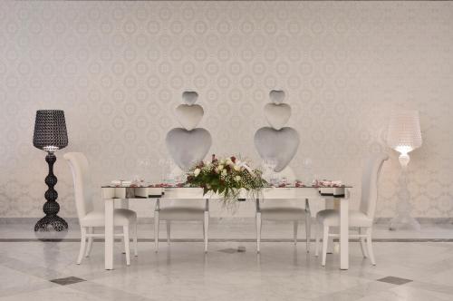 a dining room with a white table with chairs and a table with flowers at Hotel Ariston in Paestum