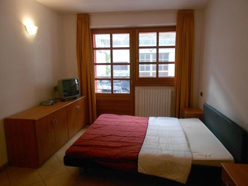 a bedroom with a bed and a tv and a window at Residence Le Orchidee in Bormio