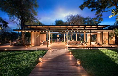 a house with a wooden walkway in the grass at Lion Sands Ivory Lodge in Sabi Sand Game Reserve