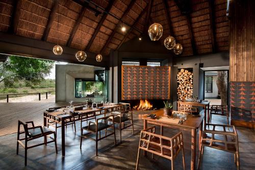 a dining room with a fireplace and tables and chairs at Lion Sands Ivory Lodge in Sabi Sand Game Reserve