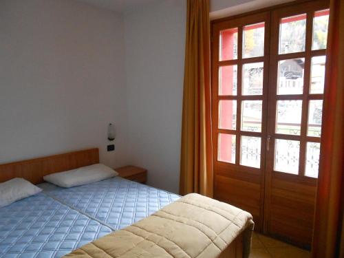 a bedroom with a bed and a large window at Residence Le Orchidee in Bormio