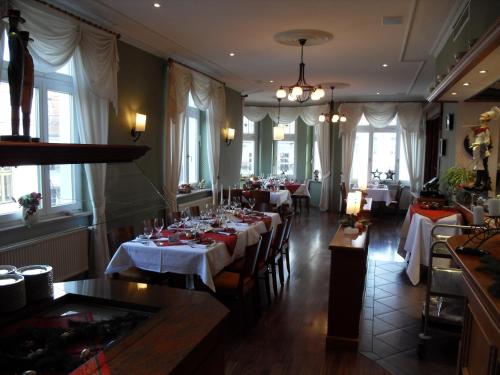 a dining room with tables with white tablecloths at Hotel Fürsteneck in Bernburg