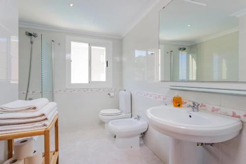 a white bathroom with a toilet and a sink at Apartamentos Amores San Telmo in Sant Elm