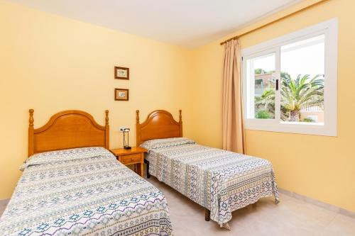 dwa łóżka w pokoju z oknem w obiekcie Apartamentos Amores San Telmo w Sant Elm