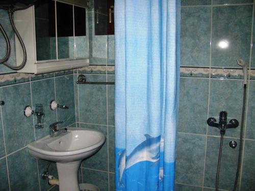uma casa de banho com um lavatório e uma cortina de chuveiro azul em MB Hotel em Žabljak