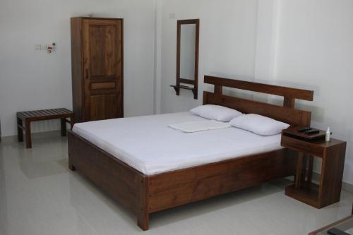 1 dormitorio con 1 cama de madera y 2 almohadas en Gem Field Rest, en Ratnapura