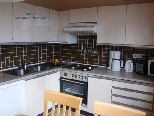 a kitchen with white cabinets and a stove top oven at Apartment Dreier - Salzburger Land in Abtenau