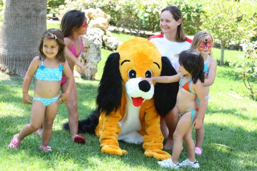 a group of girls in bathing suits standing next to a lion mascot at HSM Canarios Park in Calas de Mallorca