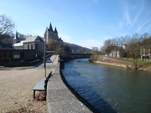 a bench next to a river with a bridge at Le poirier de Warre in Durbuy