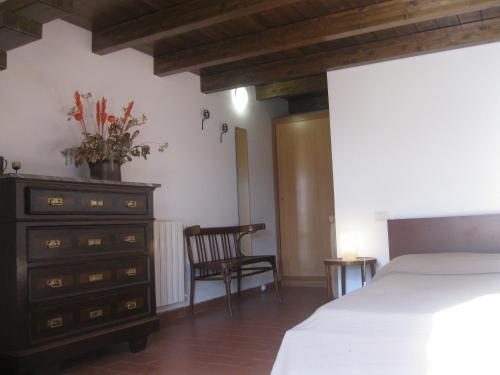 a bedroom with a bed and a dresser and a chair at B&B Sa Ingia in Càbras