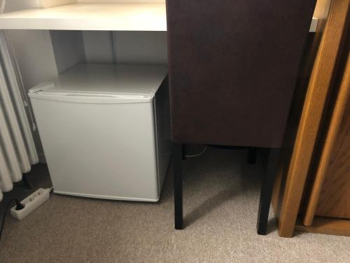 einen kleinen weißen Kühlschrank neben einem Schreibtisch und einem Tisch in der Unterkunft Kliemt room in Hilden
