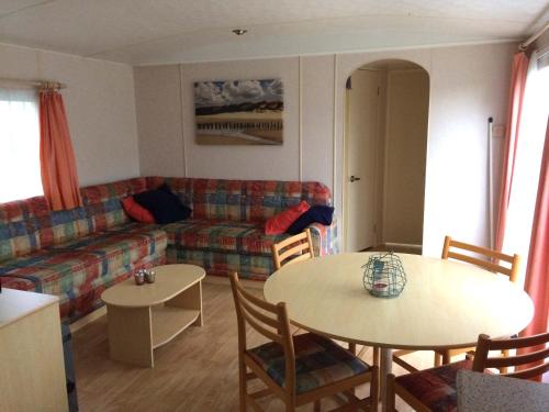 een woonkamer met een bank en een tafel en stoelen bij Minicamping Hoeve het Tij in Vrouwenpolder
