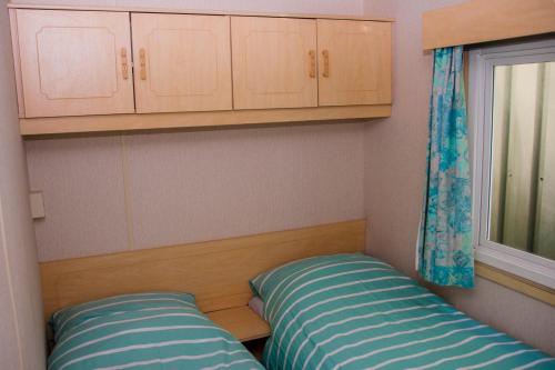 een kleine kamer met 2 bedden en een raam bij Minicamping Hoeve het Tij in Vrouwenpolder